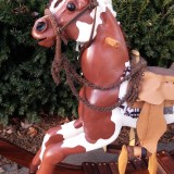 heirloom wood hand carvved rocking horse with hand made saddle and bridle, brown and white paint horse, yarn mane and tail, glass eye