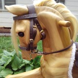 wooden rocking horse showing the head and neck with fully functioning leather bridle with buckles and bit.