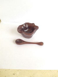 walnut carved salt bowl and tiny carved walnut spoon on white background