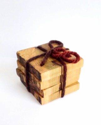 square wood coasters in poplar wood in a stack with a variegated brown yarn string holding them together with a bow.
