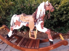 heirloom wood hand carvved rocking horse with hand made saddle and bridle, brown and white paint horse, yarn mane and tail, glass eye