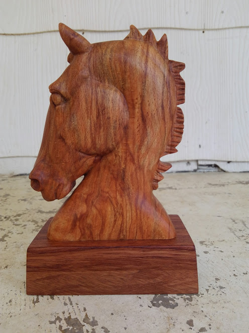 hand carved horse head photographed on porch with peeling white paint. Side view of left side